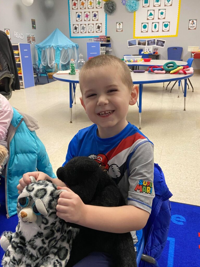 Student smiling with stuffed animals in Potential Development classroom