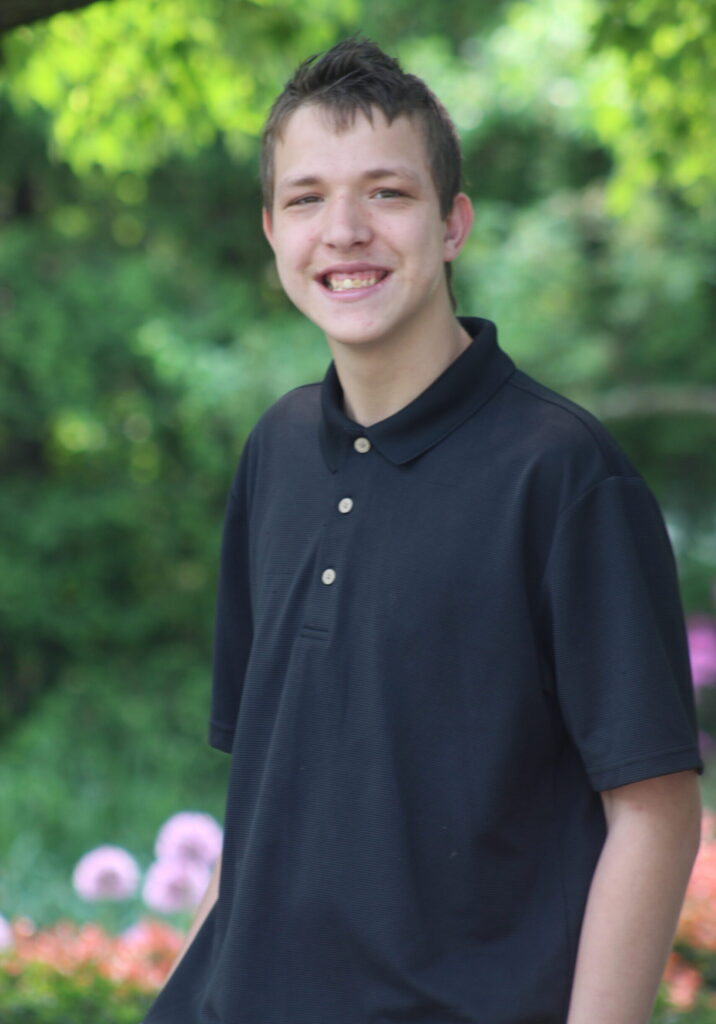 Student smiling outside wearing black polo for senior photos