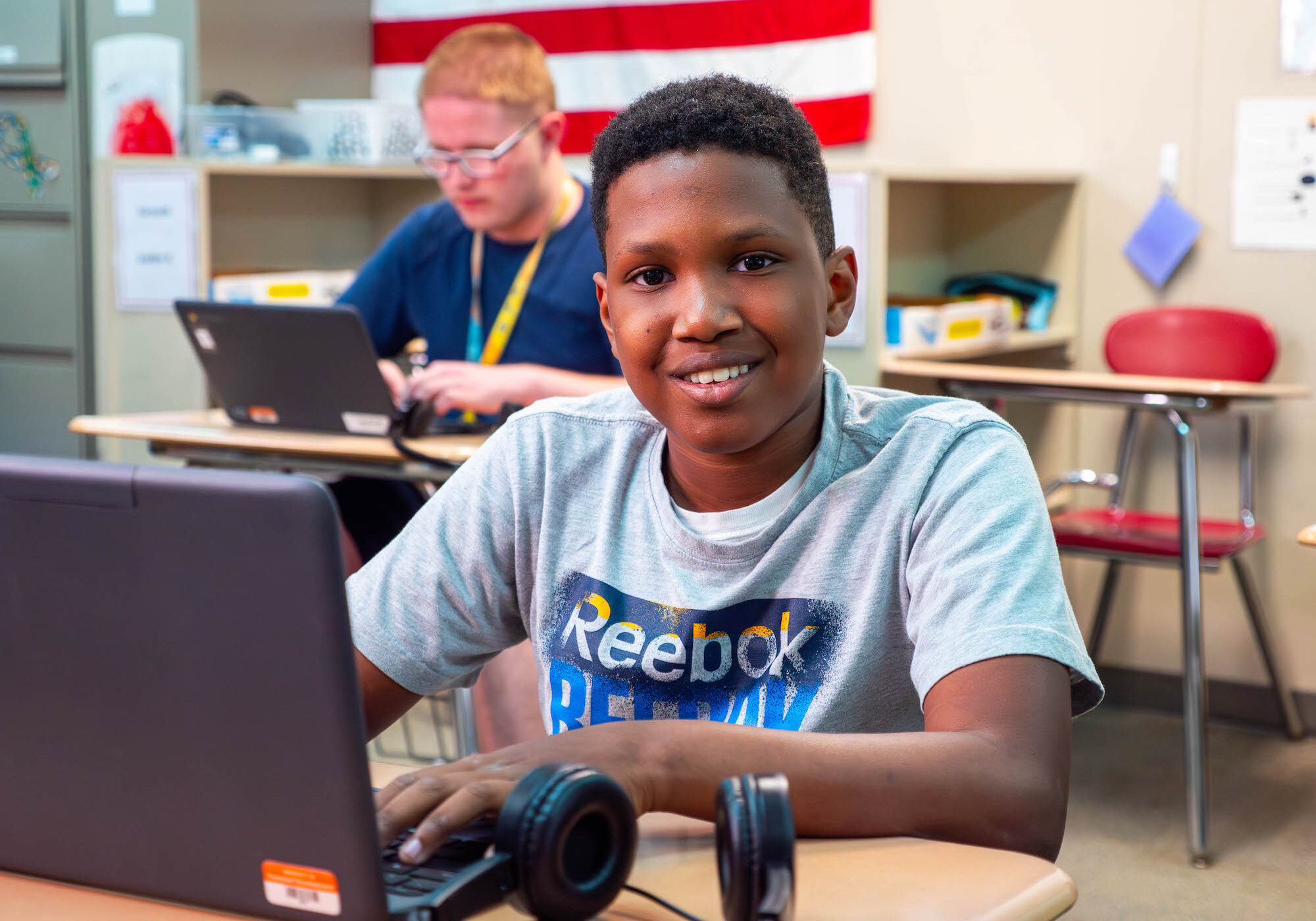 Student smiling and working on computer in the classroom
