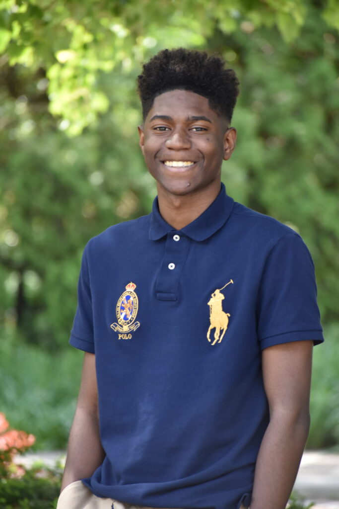 Potential development student wearing polo shirt smiling outside for his senior photos